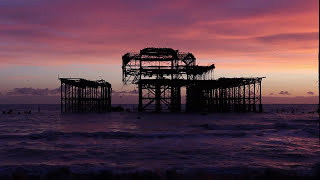 a haunting image of the West Pier, Brighton silhouetted against the bruised hues of a sunset sky