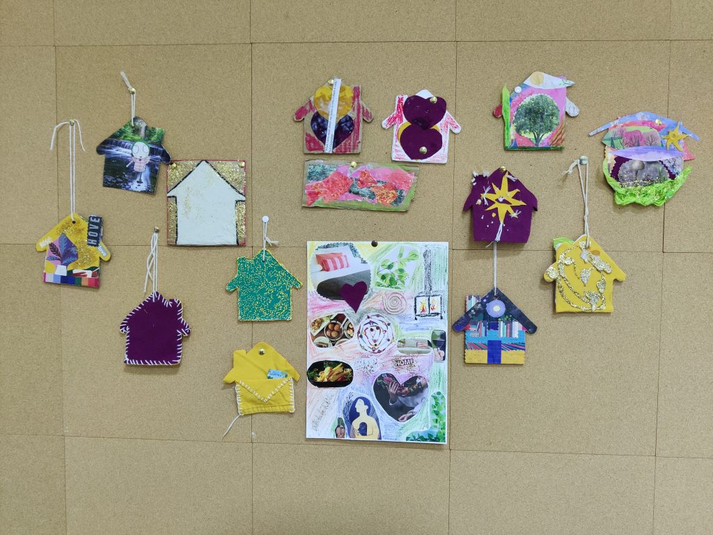 picture shows several tiny homes from soft material or clay or cardboard or card and stuck to a corkboard with string and pins